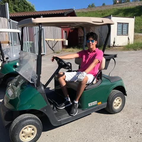 John sitting in a golf cart on a sunny summer day
