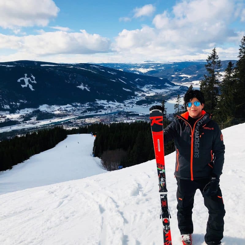 John standing on a ski slope holding his skis